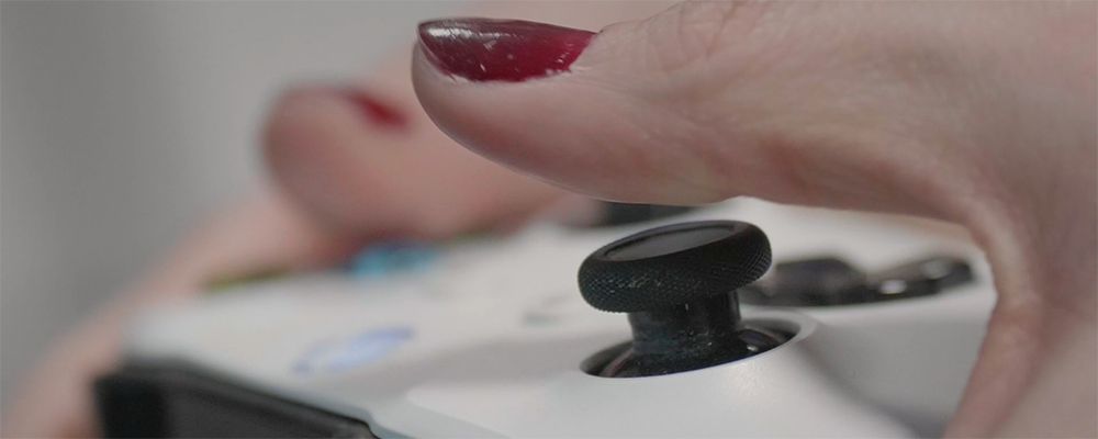 Illustration : mains féminines maniant une manette de jeux vidéo.